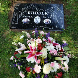 Floral grave arrangement below a memorial headstone