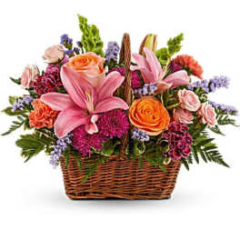 Basket arrangement with pink lilies, orange roses, and purple flowers