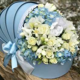 Blue and white bouquet with roses and hydrangeas in a round hatbox