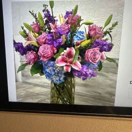 Tall vase arrangement with pink roses, lilies, purple stock, and blue hydrangeas