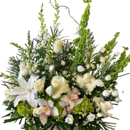 Large white floral arrangement in a basket with tall green spikes