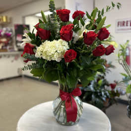 Red roses and white hydrangea in a glass vase with a red ribbon