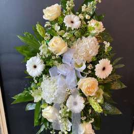 White floral standing spray with roses, gerberas, and hydrangea on an easel