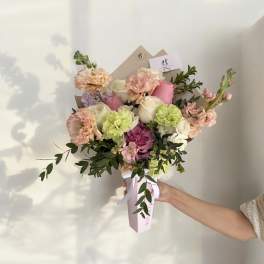 Handheld bouquet of pink, white, and peach flowers with greenery
