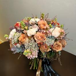 Peach roses and white blooms arranged in a hand-tied bouquet