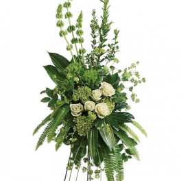 Tall green and white standing arrangement with roses, bells of Ireland, and lush greenery.
