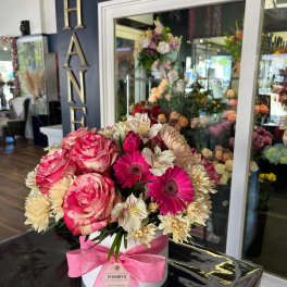 Pink and cream mixed flower arrangement in a white hat box with a pink ribbon