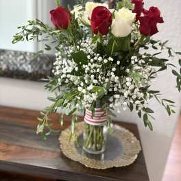 Red and white roses in a glass vase with baby's breath