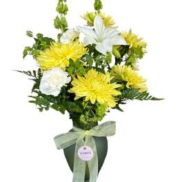 Yellow and white floral arrangement in a dark vase with a ribbon