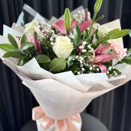Bouquet of pink lilies and white roses wrapped in white paper