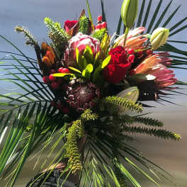 Tropical bouquet with protea, lilies, and red roses