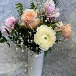 Pastel bouquet of roses and ranunculus in a white vase