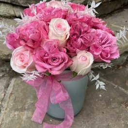 Pink and white rose bouquet in a gray container with a pink ribbon
