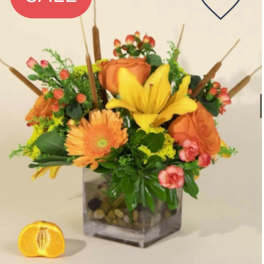 Orange and yellow floral arrangement in a square glass vase