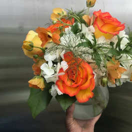 Bouquet of orange and yellow roses with white flowers in a glass vase