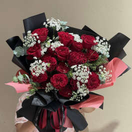 Bouquet of red roses with white filler flowers and black-and-pink wrapping