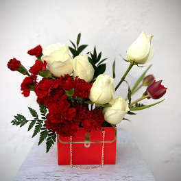 Red carnations and white roses in a red gift box