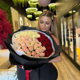 Large bouquet of pink, cream, and red roses wrapped in black paper