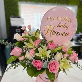 Pink and white floral arrangement with a baby shower balloon
