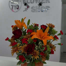 Orange lilies and red roses in a pumpkin-shaped container