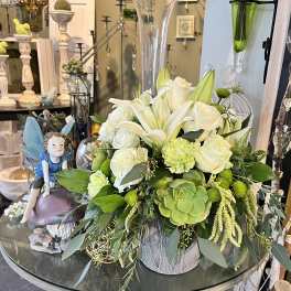 White roses and lilies in a silver container with green succulents