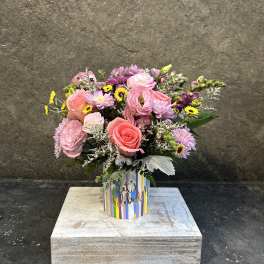 Pink and lavender mixed bouquet in a striped "let's celebrate" container