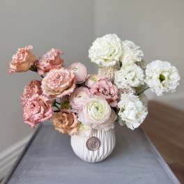 Pink and white flowers arranged in a white vase