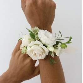 White floral wrist corsage on a person's wrist
