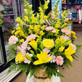 Basket arrangement of yellow lilies, roses, snapdragons, and pink carnations