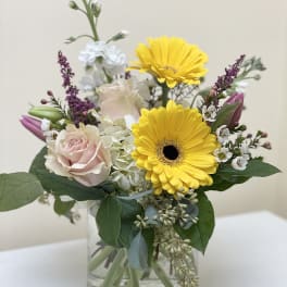Bouquet of yellow gerbera daisies and pale pink roses in a glass vase