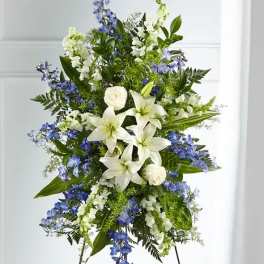 Standing floral spray with white lilies, white roses, and blue flowers