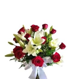 Red roses and white lilies in a clear vase with a white ribbon