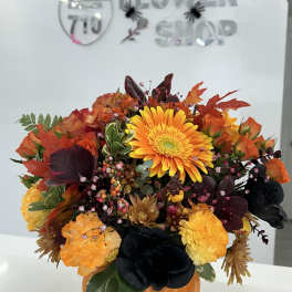 Autumn floral arrangement in an orange pumpkin vase with orange and yellow blooms