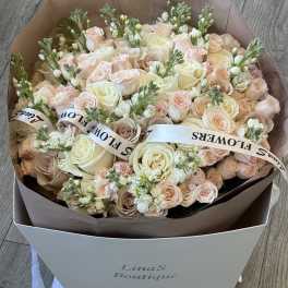 Large bouquet of pale pink and cream roses with white blooms in a box