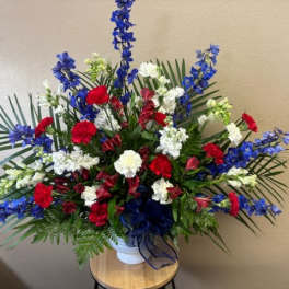 Large red, white, and blue floral arrangement in a white vase