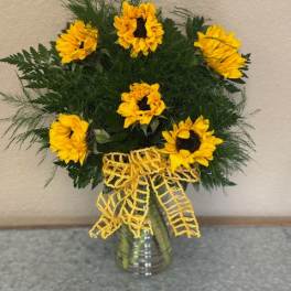 Sunflower arrangement in a glass vase with a yellow ribbon