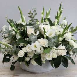 White floral arrangement in a low gray bowl with green accents