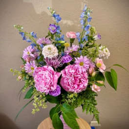 Pink peonies and purple-blue mixed flowers in a pink vase