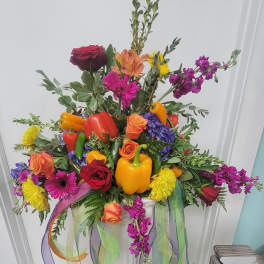 Colorful floral arrangement with peppers and ribbon streamers in a white container