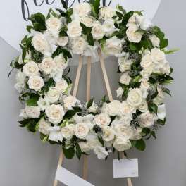 White rose wreath on a wooden easel with greenery