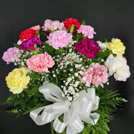 Bouquet of multicolored carnations in a glass vase with a white ribbon