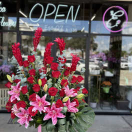 Tall bouquet of red roses and pink lilies in a pink vase