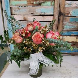 Pink roses arranged in a glass vase with lace ribbon