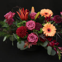 Mixed bouquet with pink roses, orange gerbera daisies, and red blooms