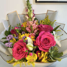Bouquet of pink roses, yellow flowers, and white lilies in gray wrap