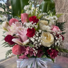 Mixed bouquet of pink and white flowers in a glass vase with ribbon