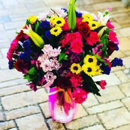 Colorful mixed bouquet in a pink vase with roses and lilies