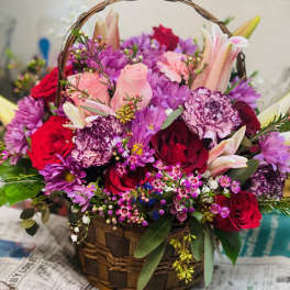 Basket arrangement of pink, red, and purple flowers with lilies and roses