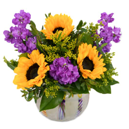 Sunflowers and purple flowers arranged in a glass vase