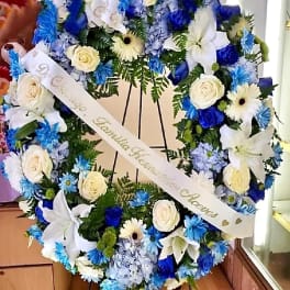 Large blue and white floral wreath with a memorial ribbon